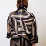 Person wearing a black and white patterned jacket on a plain background