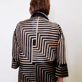 Person wearing a black and white patterned jacket on a plain background