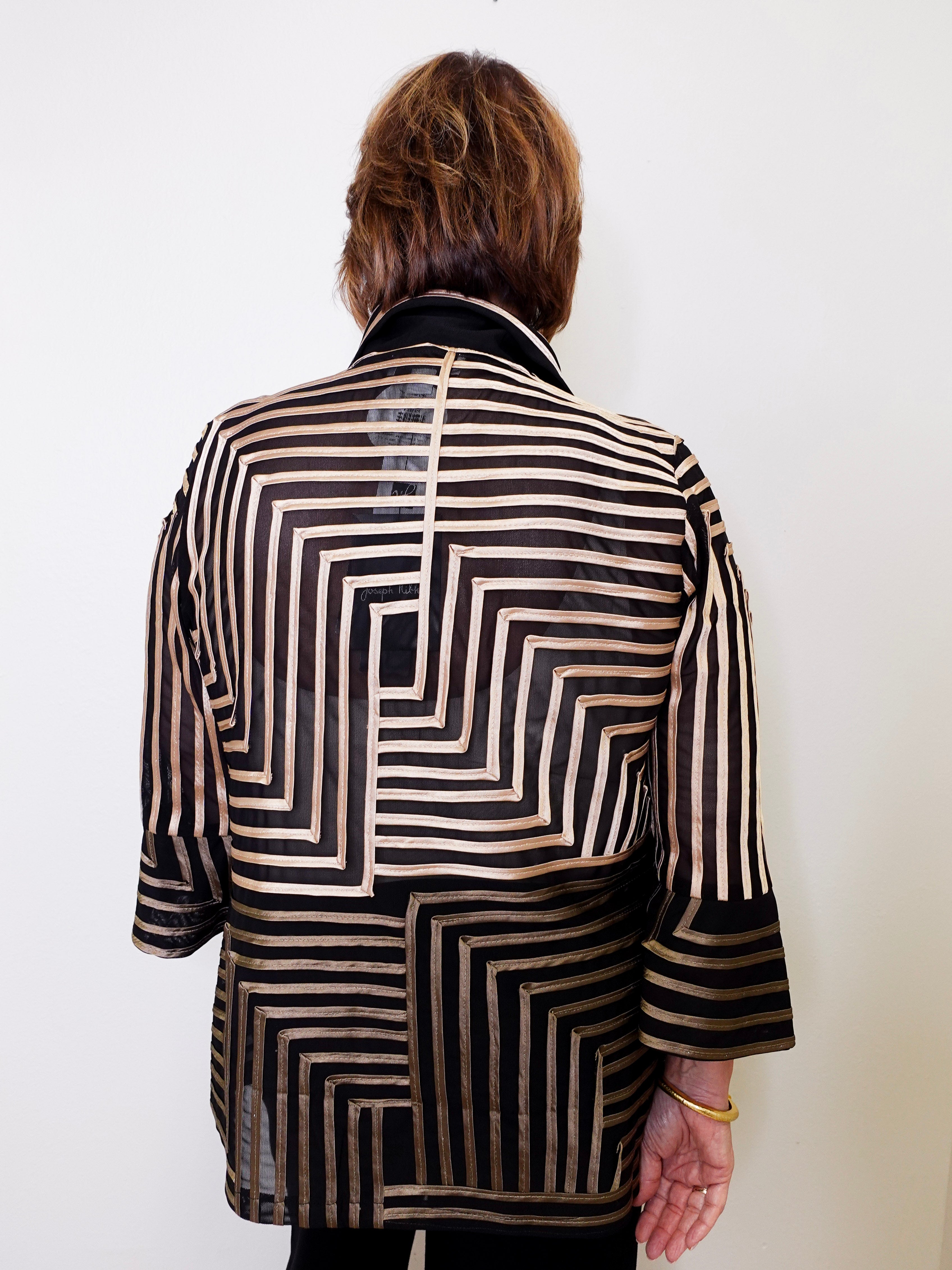 Person wearing a black and white patterned jacket on a plain background