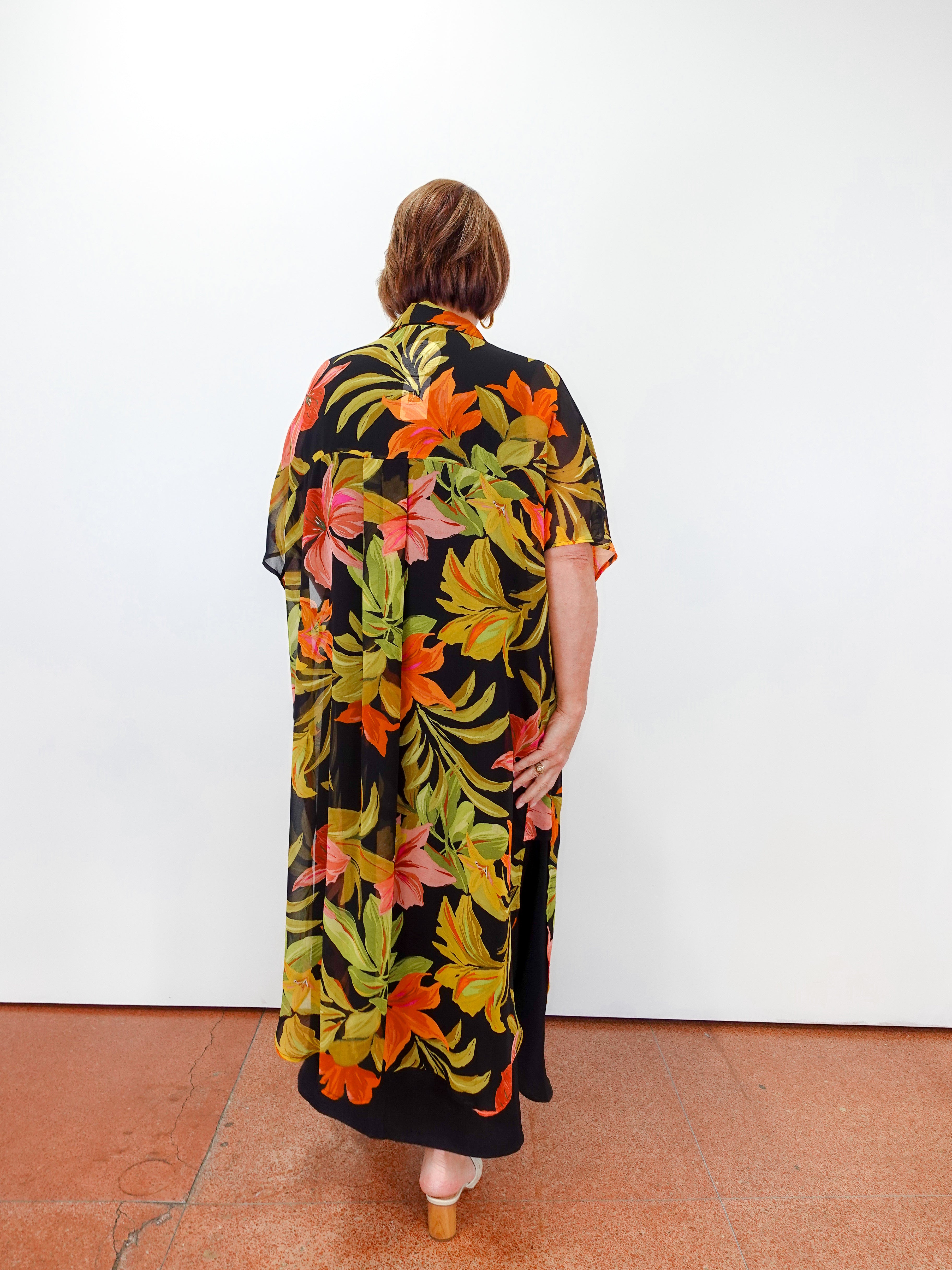 Person wearing a colorful floral dress with a black background
