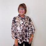 A woman wearing a Joseph ribkoff cowl neck leopard print pullover sweater in front of a white wall. 