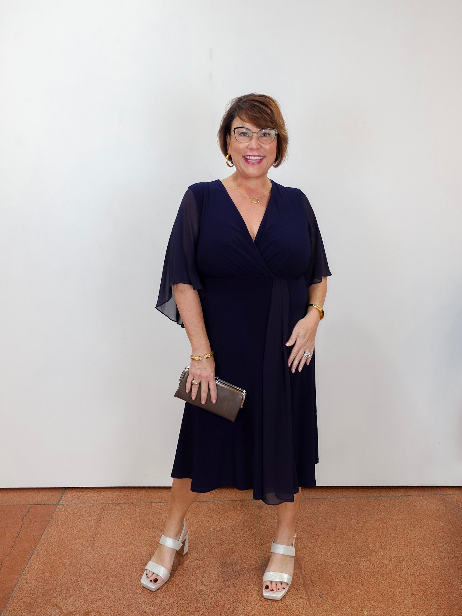 Model wearing a Joseph Ribkoff fit and flare dress in navy with a v-neckline and flowy short sleeves.