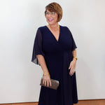 Model wearing a Joseph Ribkoff fit and flare dress in navy with a v-neckline and flowy short sleeves.