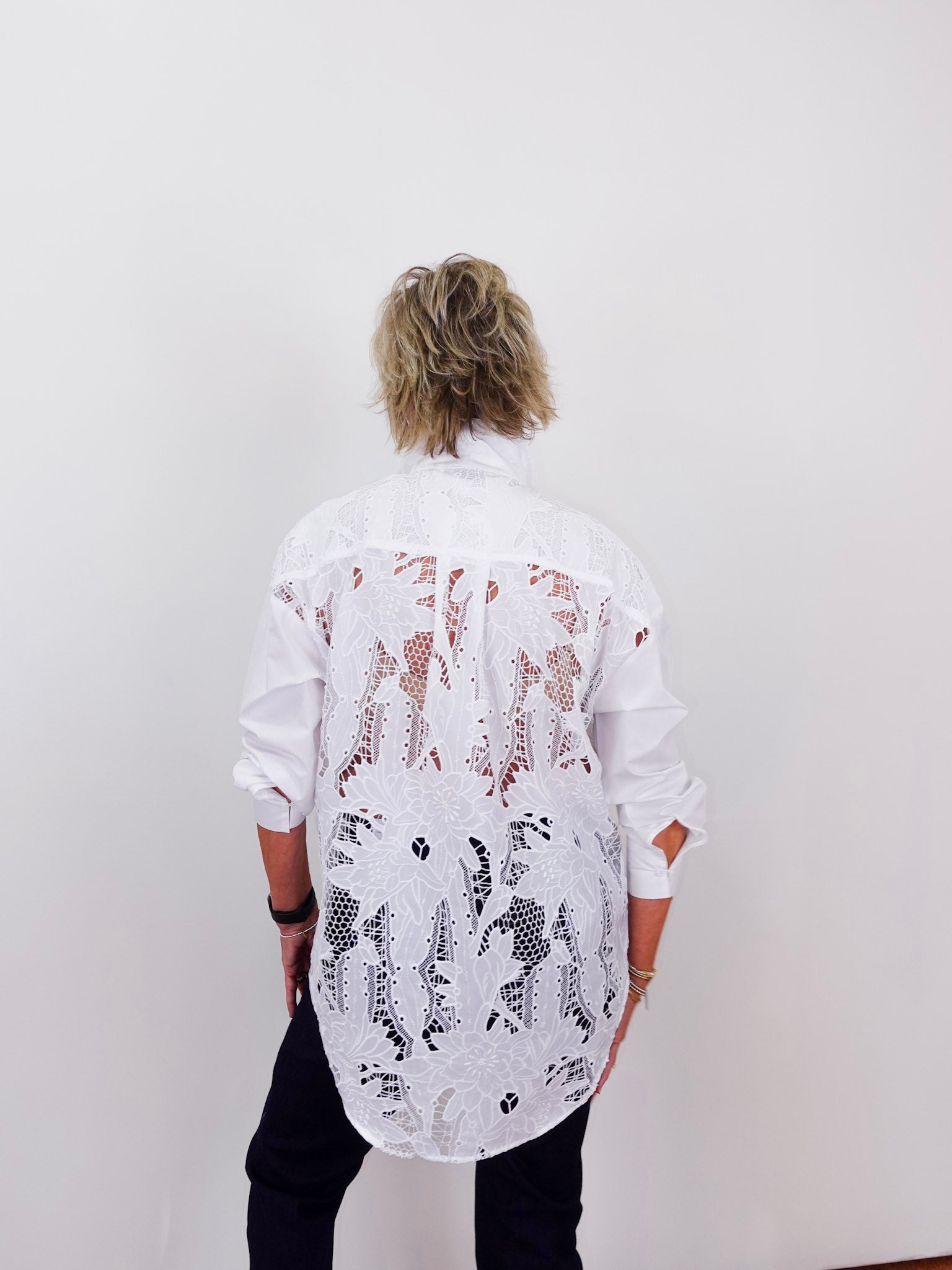 Person wearing a white shirt with black and brown pattern against a plain background