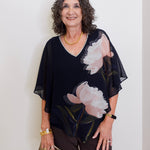 Woman wearing a black floral blouse against a white background