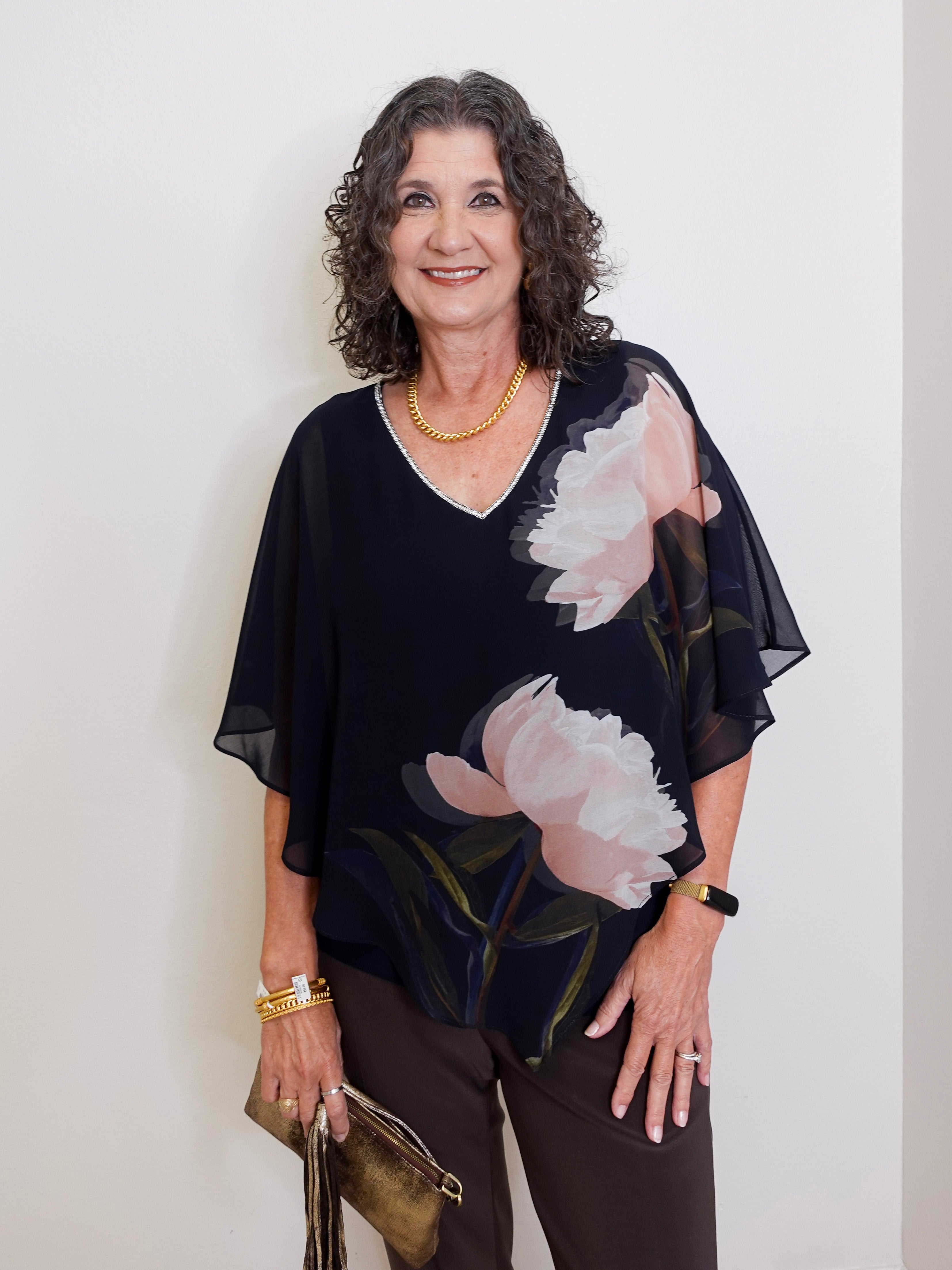 Woman wearing a black floral blouse against a white background
