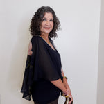Woman wearing a black outfit with cut-out shoulders against a white background