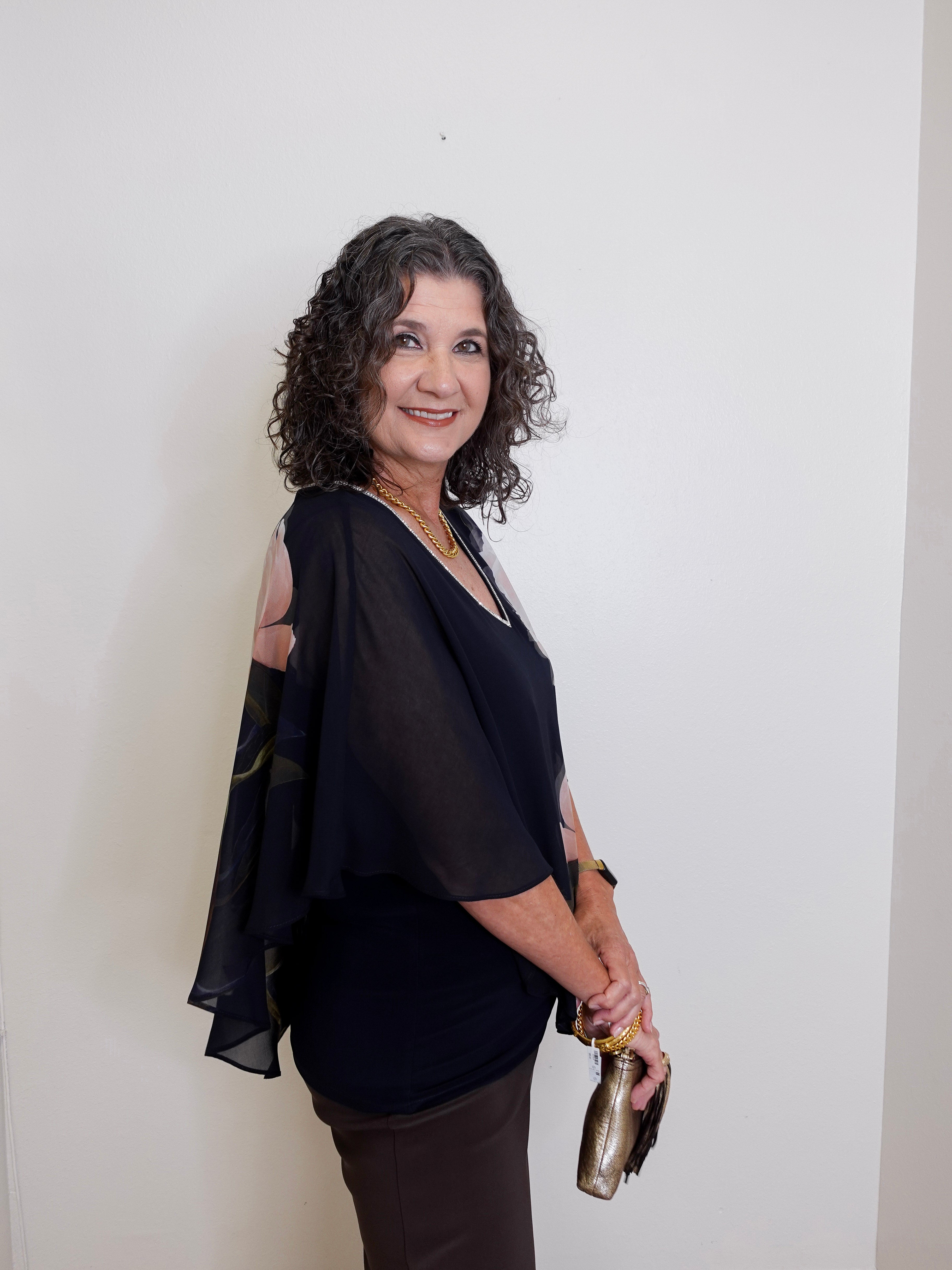 Woman wearing a black outfit with cut-out shoulders against a white background