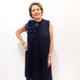 Model wearing a Joseph Ribkoff high neck A-line dress in navy with pleated fabric and floral appliqué detail.