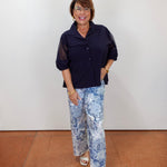 Model wearing a Joseph Ribkoff poplin and mesh boxy blouse in navy with button-front design and sheer short sleeves.