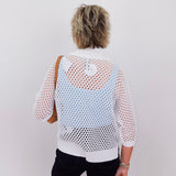 Person wearing a white mesh top with a plain background