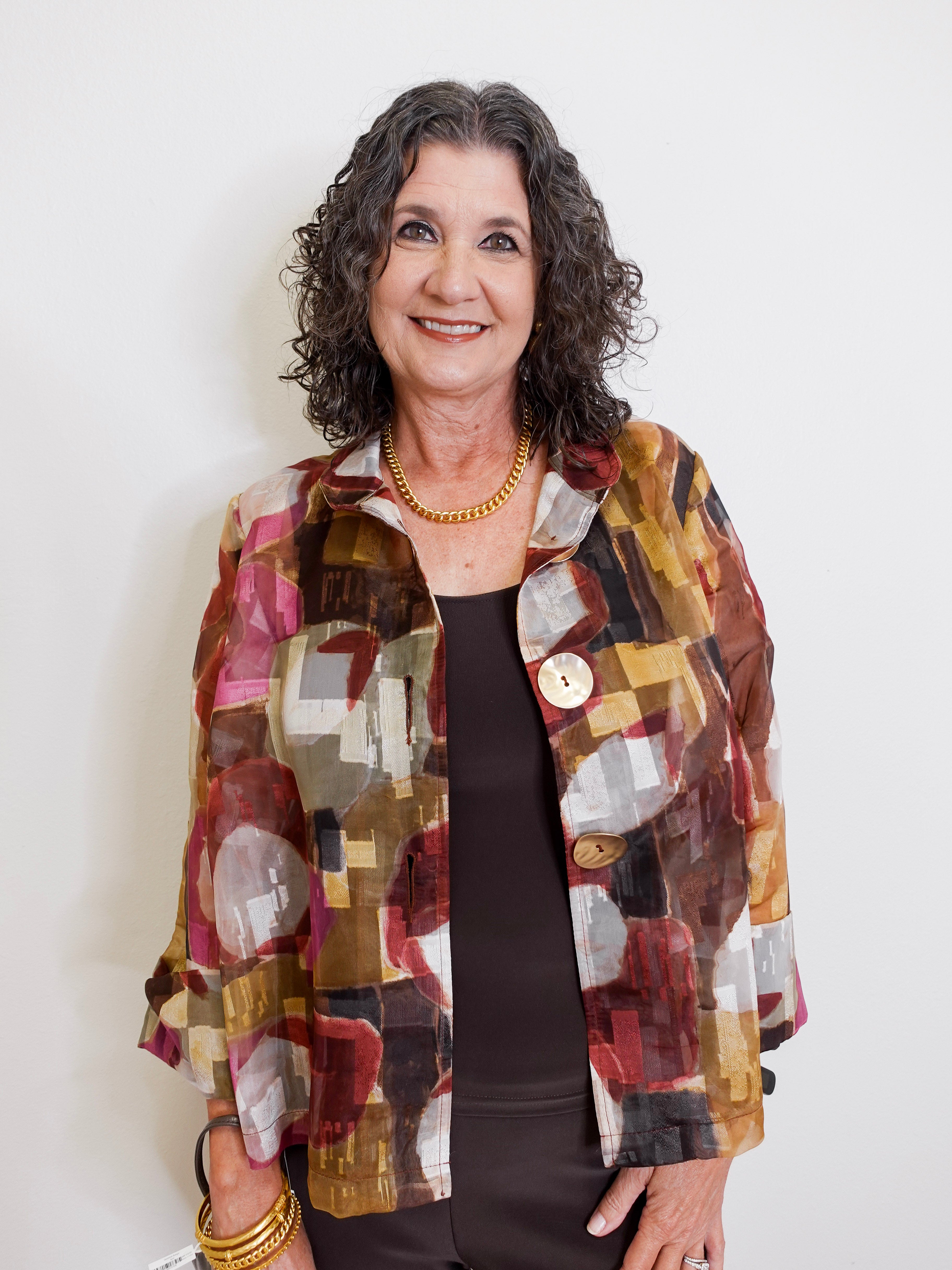Woman wearing a colorful patterned jacket against a white background