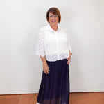 Model wearing a Joseph Ribkoff white polka dot blouse with sheer sleeves and button-front design.