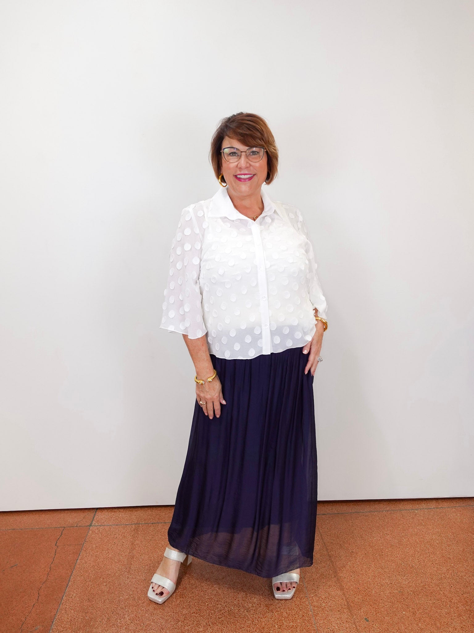Model wearing a Joseph Ribkoff white polka dot blouse with sheer sleeves and button-front design.