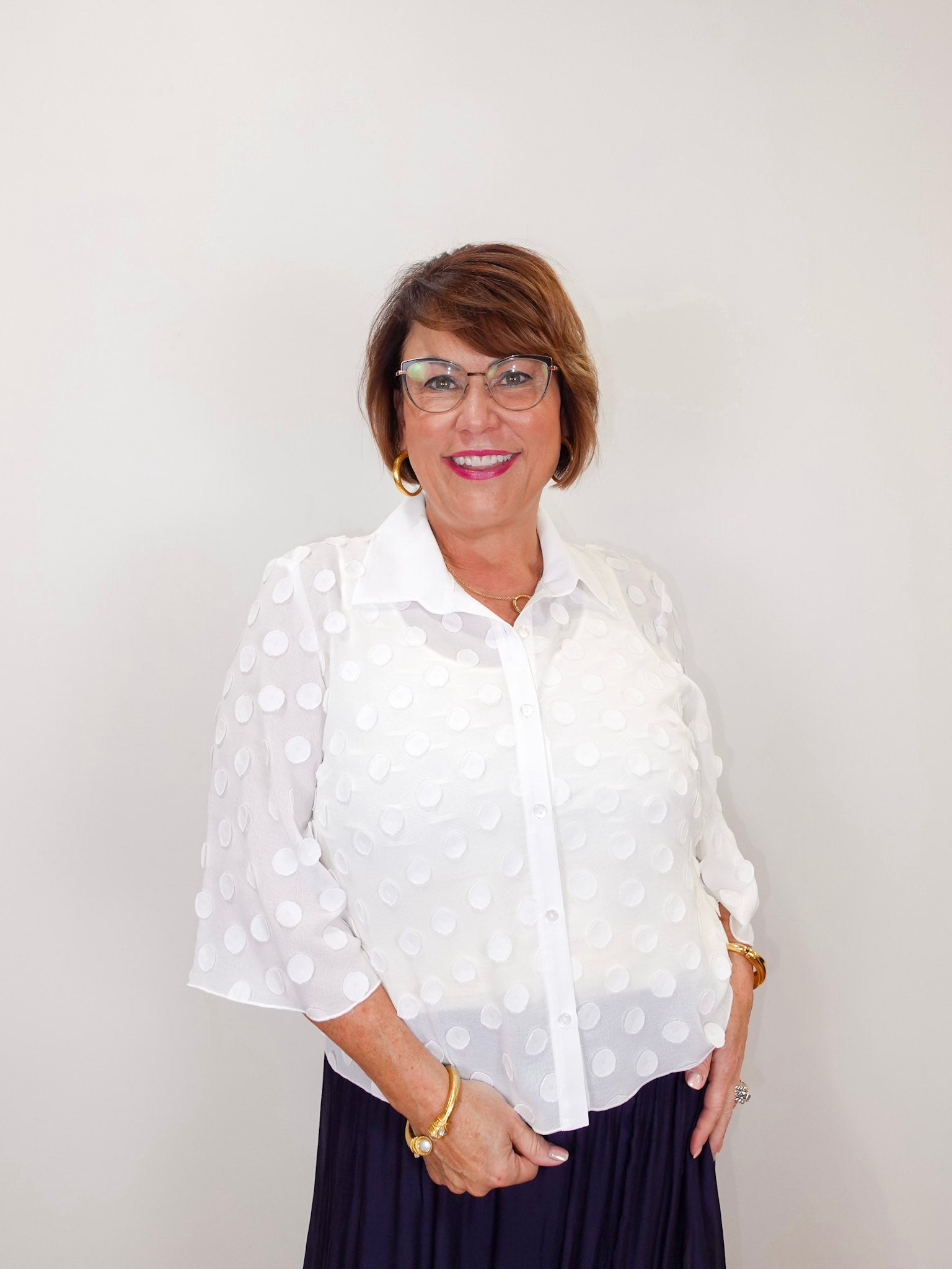 Woman modeling a Joseph Ribkoff white polka dot blouse featuring a lightweight sheer fabric, button-front closure, and relaxed fit.