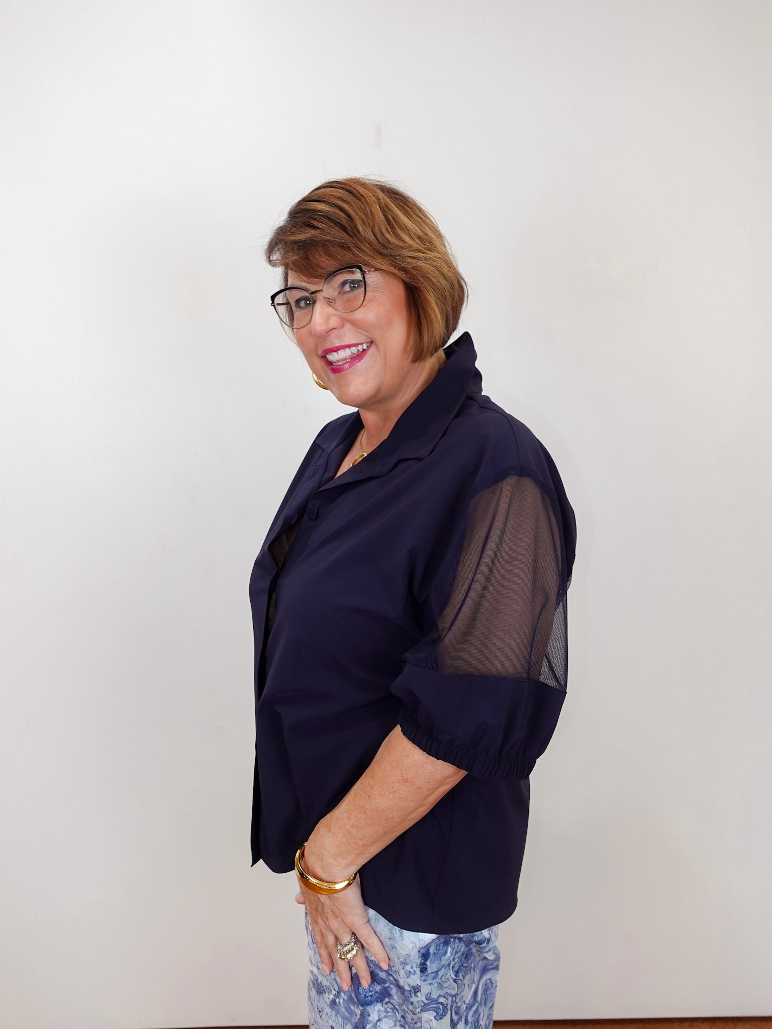 Woman modeling a Joseph Ribkoff poplin and mesh boxy blouse featuring a navy button-front design, relaxed fit, and sheer sleeve panels.