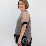 Woman holding a black handbag against a white wall