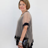 Woman holding a black handbag against a white wall