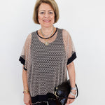 Woman wearing a patterned top and black pants with a white background