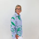 Person wearing a patterned shirt with green and blue design against a white background
