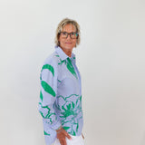 Person wearing a patterned shirt with green and blue design against a white background