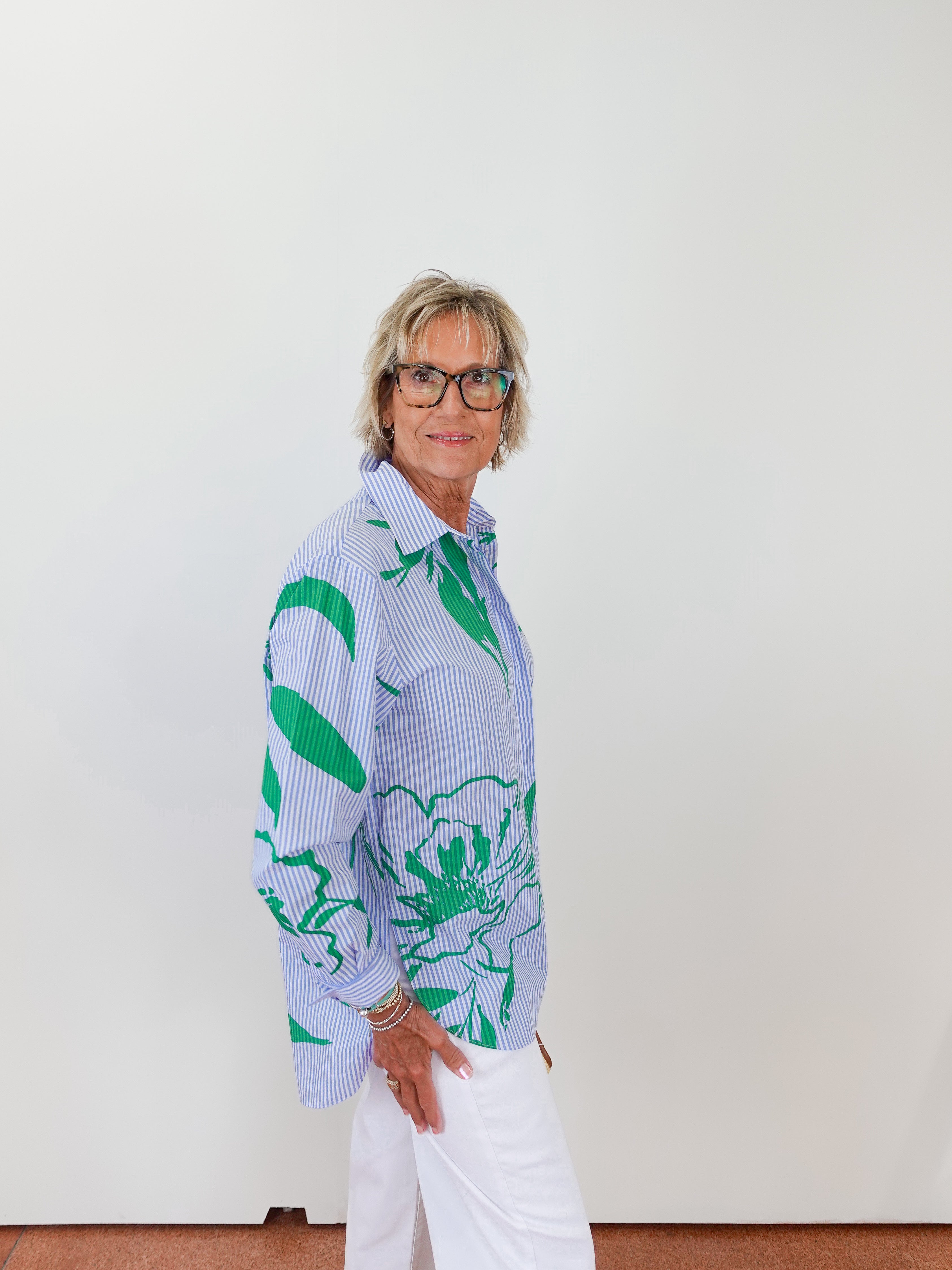 Person wearing a patterned shirt with green and blue design against a white background