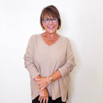 A women wearing a v-neck jewel embellished sweater in front of a white wall.