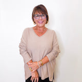 A women wearing a v-neck jewel embellished sweater in front of a white wall.