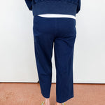 Person wearing navy blue pants and a matching top on a plain background