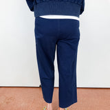 Person wearing navy blue pants and a matching top on a plain background