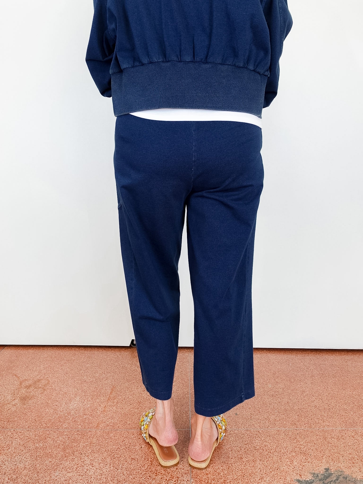 Person wearing navy blue pants and a matching top on a plain background
