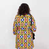 Person wearing a colorful patterned dress against a white background