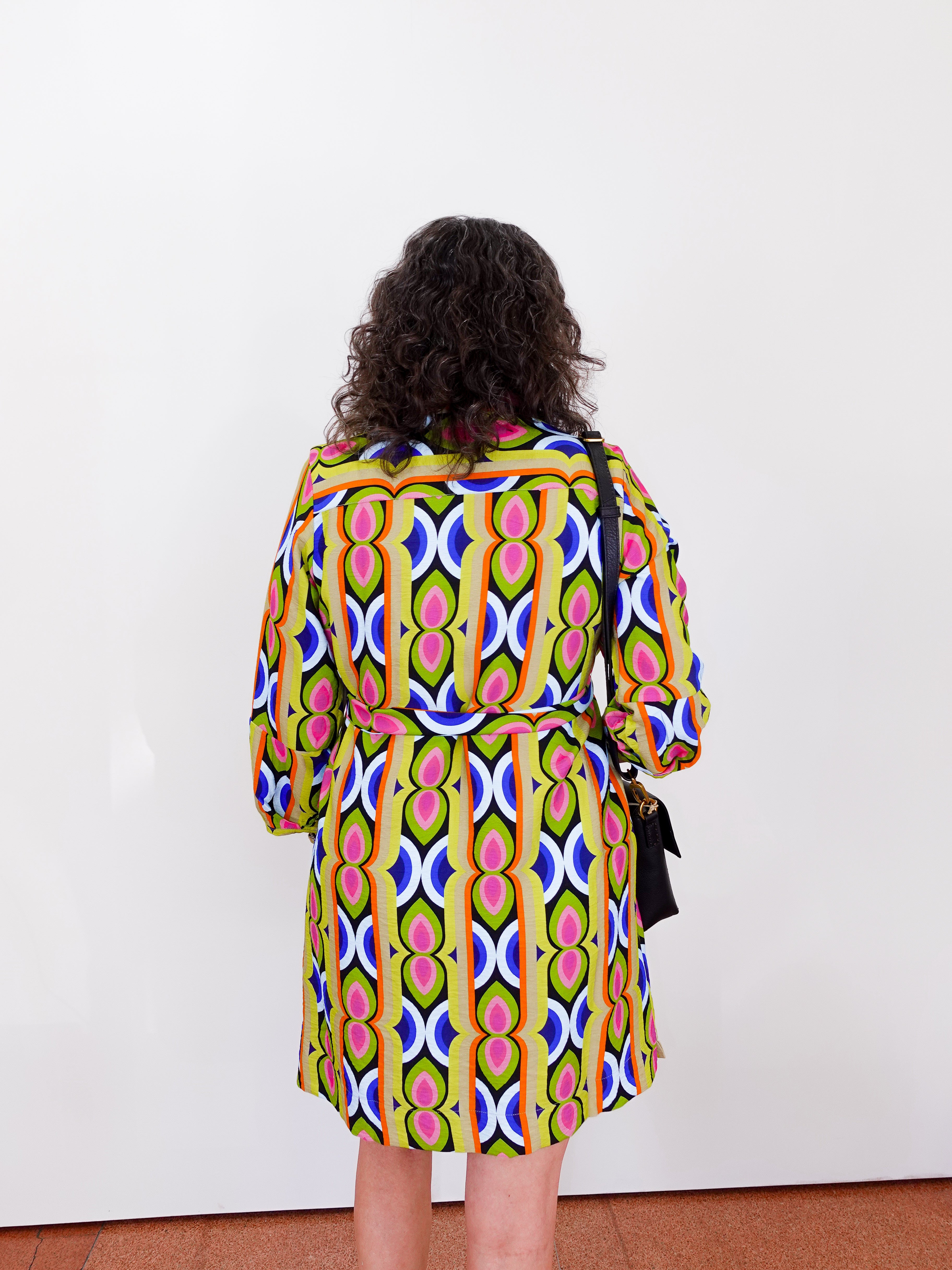 Person wearing a colorful patterned dress against a white background
