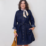 Woman wearing a denim dress with a white wall background