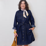 Woman wearing a denim dress with a white wall background