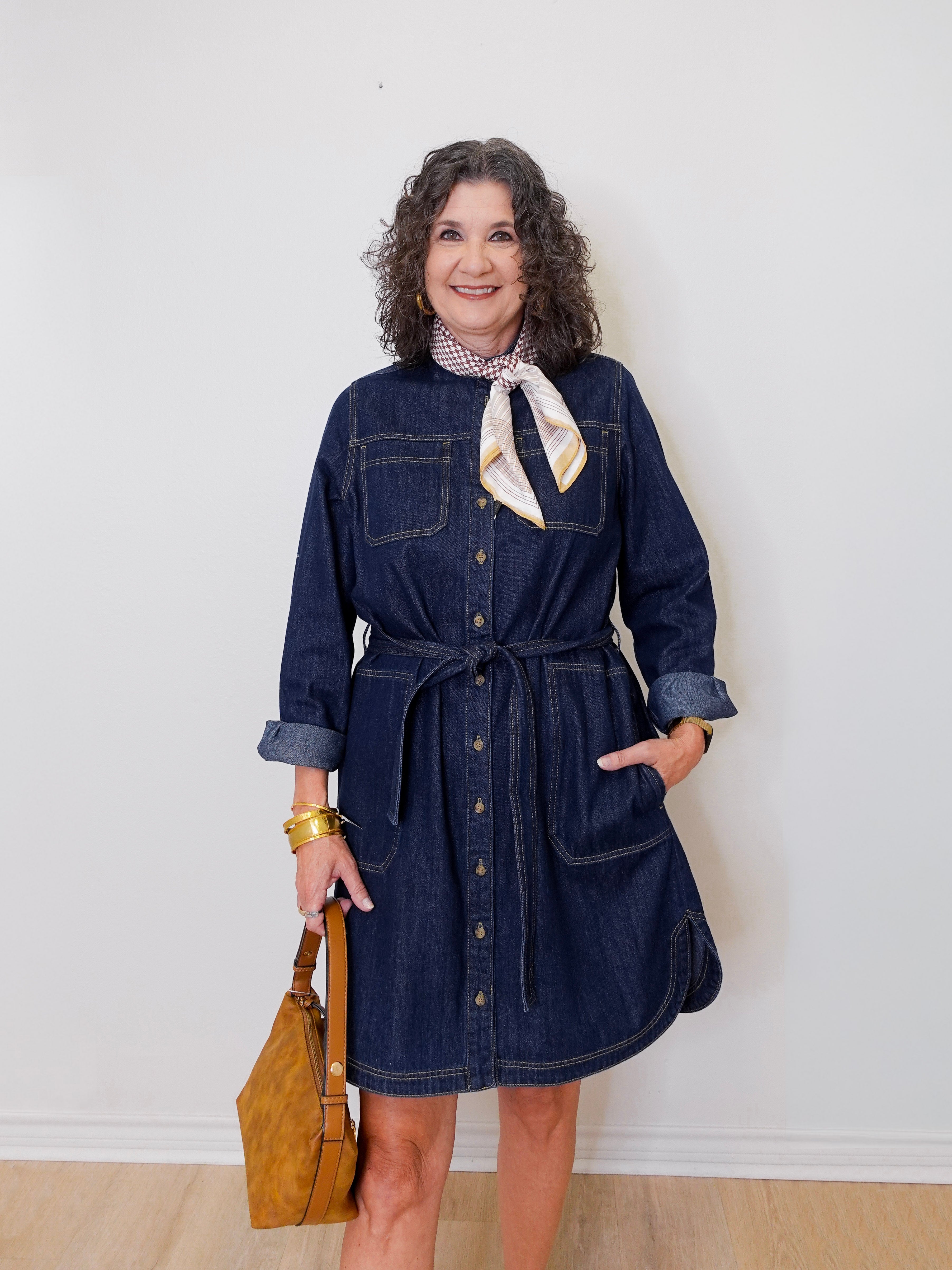 Woman wearing a denim dress with a white wall background
