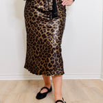 Person wearing a leopard print skirt with a plain white background