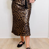 Person wearing a leopard print skirt with a plain white background