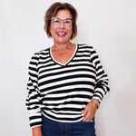 Woman wearing a black and white  Karen Kane striped shirt with blue jeans against a white background