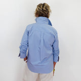 Person wearing a light blue jacket and beige pants against a white background