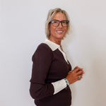 Woman wearing a brown and white sweater against a plain background