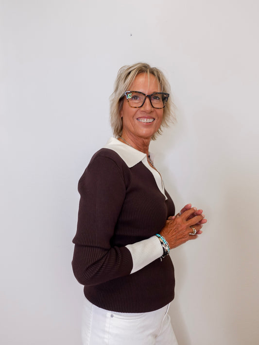 Woman wearing a brown and white sweater against a plain background