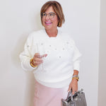 woman wearing a cream sweater against a  white background. 