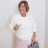 woman wearing a cream sweater against a  white background. 