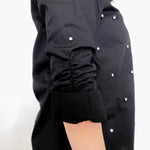 Black shirt with white buttons on a plain background
