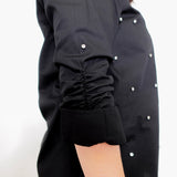 Black shirt with white buttons on a plain background