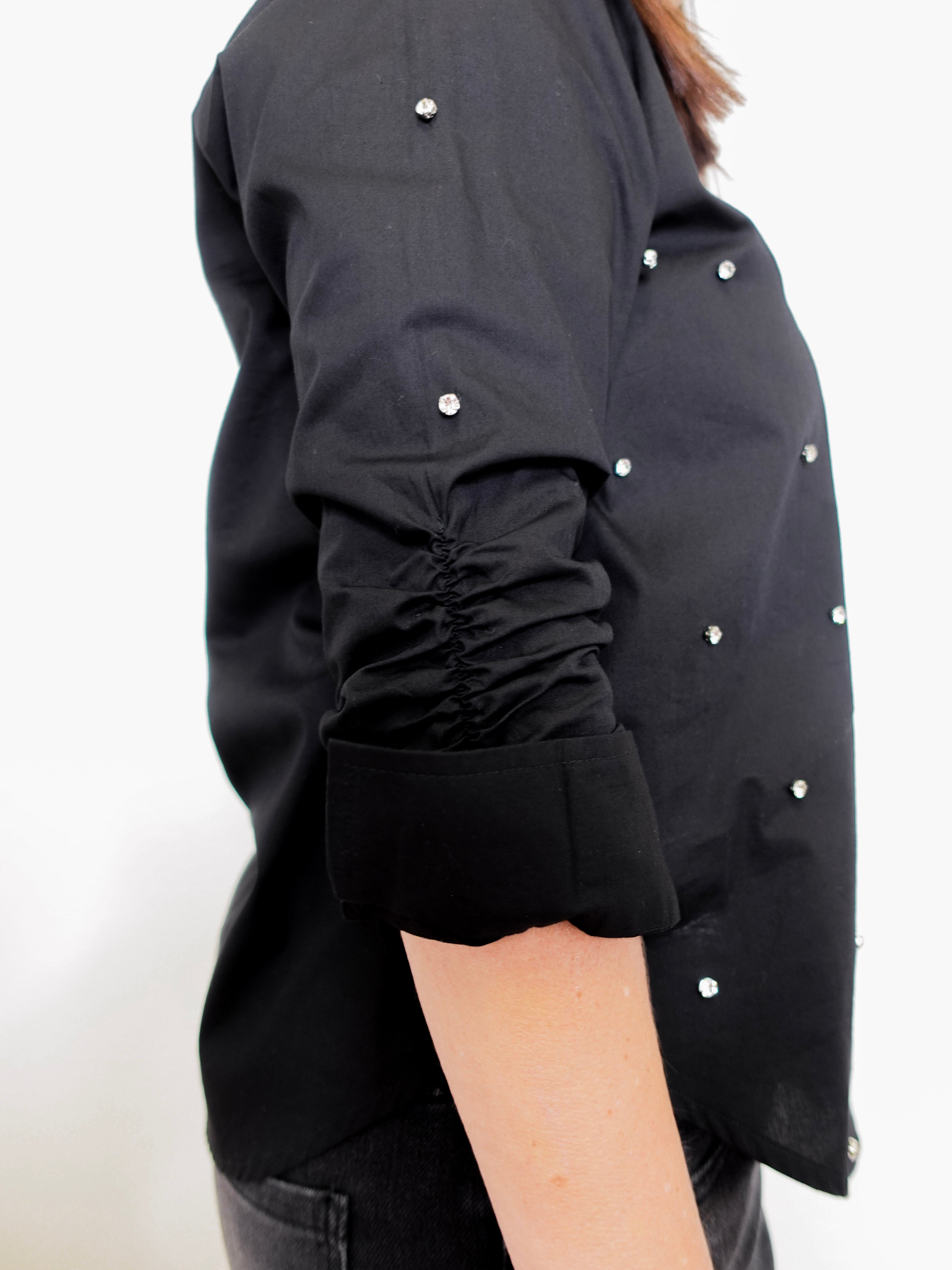 Black shirt with white buttons on a plain background