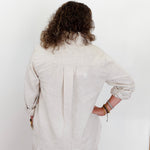 Person wearing a light-colored outfit against a white background