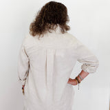 Person wearing a light-colored outfit against a white background