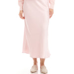 Person wearing a light pink skirt and top on a white background